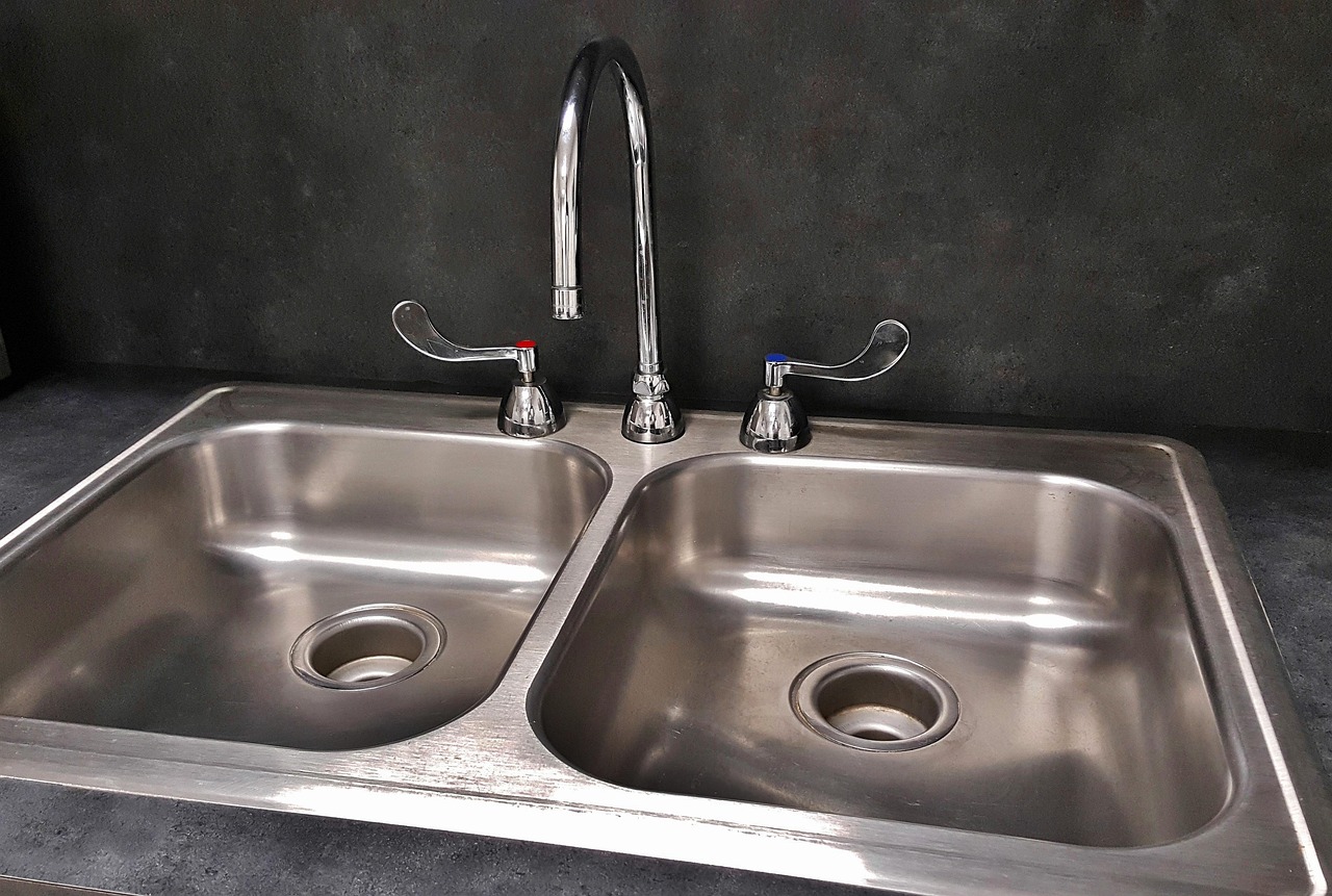 Dried white water spots on a dark kitchen countertop beside a faucet